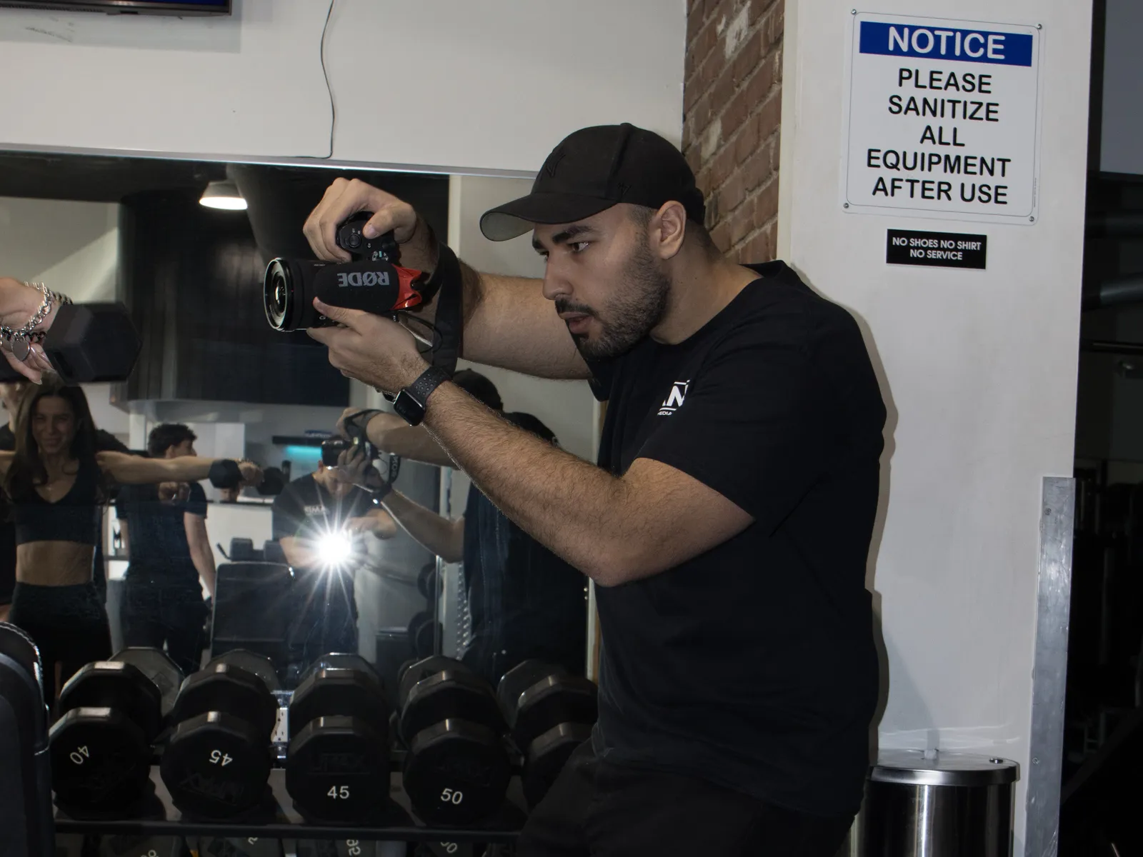 Aspire camera operator in a black shirt filming with a camera rig during a gym shoot