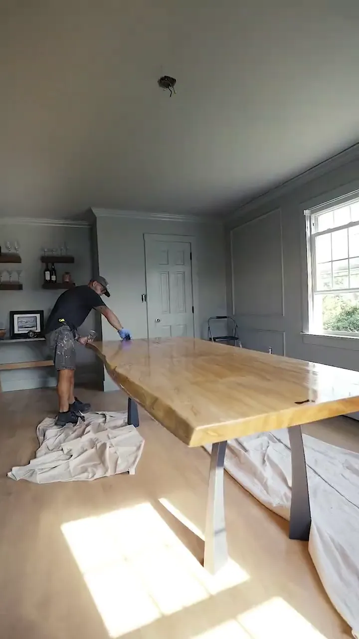 A finished live-edge slab dining table on steel legs in a bright room, from Jetty Woodwork's start-to-finish reel