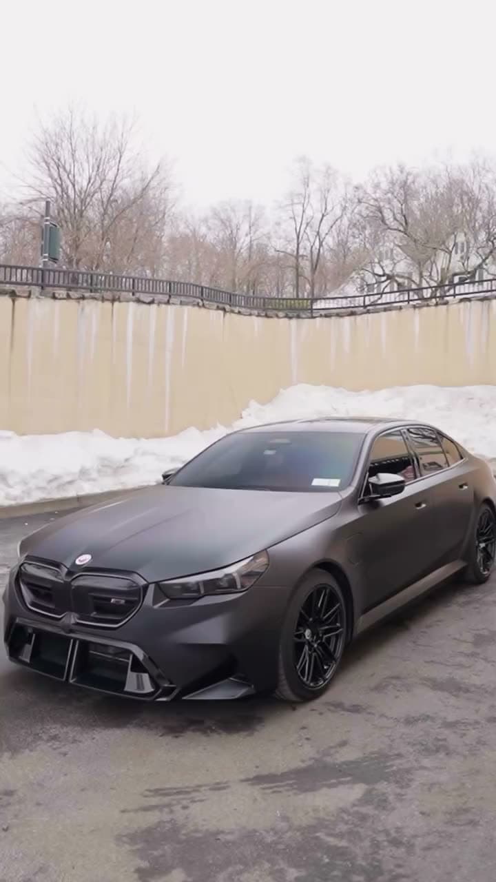 Satin black BMW M5 after a paint-protection film install, parked by a snowy lot