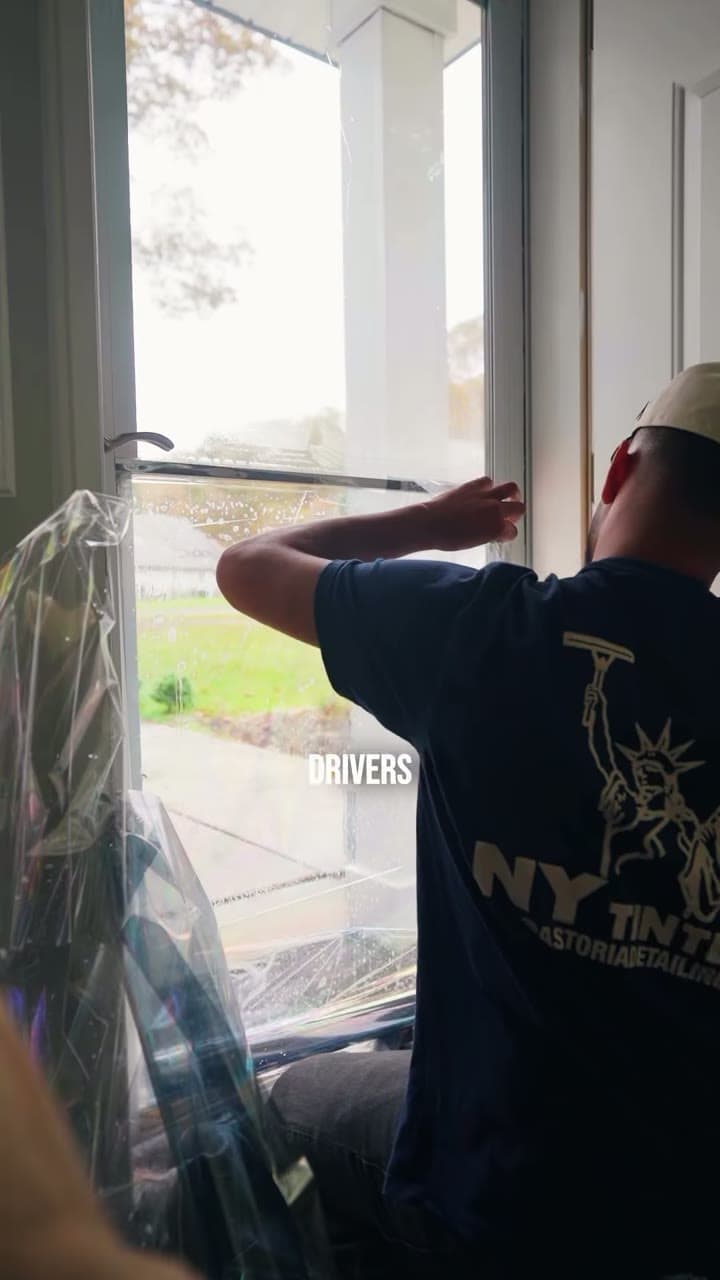 Installer fitting window tint inside a customer's home, from a residential window-tint ad for a Queens detailing studio